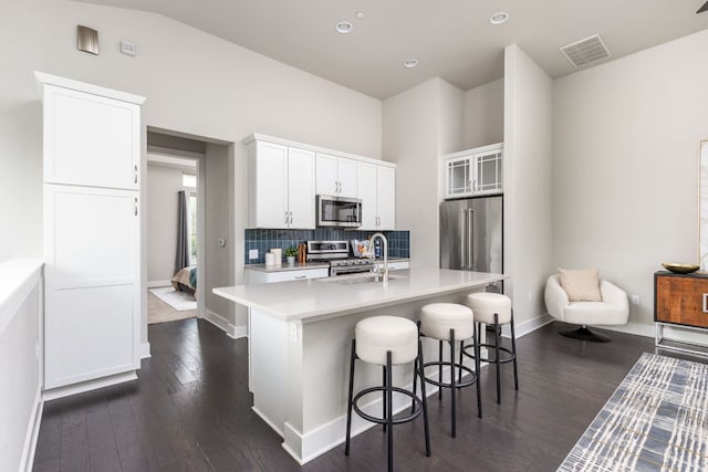 404 W Alpine Rd Unit 1, Austin, TX 78704 - kitchen with appliances with stainless steel finishes, dark wood-style flooring, light countertops, a kitchen bar, and white cabinets