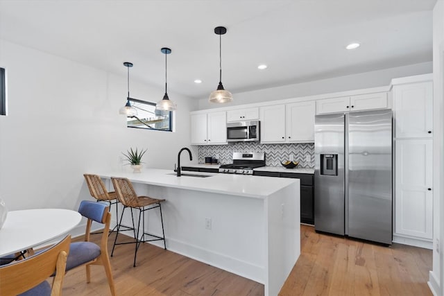 2102 Eva St Unit 2, Austin, TX 78704 - kitchen featuring appliances with stainless steel finishes, a peninsula, backsplash, light wood-style flooring, and white cabinetry