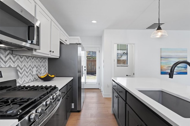 2102 Eva St Unit 2, Austin, TX 78704 - kitchen featuring stainless steel appliances, white cabinets, light countertops, decorative light fixtures, and light wood-type flooring
