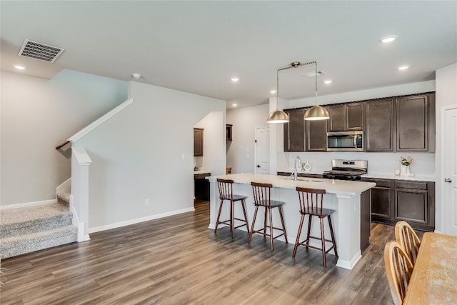 970 Lone Peak Way, Dripping Springs, TX 78620 - kitchen with appliances with stainless steel finishes, a kitchen bar, dark wood-style floors, dark brown cabinets, and recessed lighting