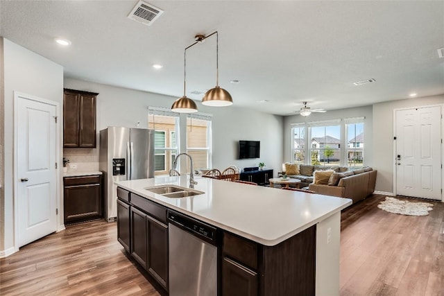 970 Lone Peak Way, Dripping Springs, TX 78620 - kitchen featuring stainless steel appliances, dark brown cabinets, light countertops, light wood-type flooring, and pendant lighting