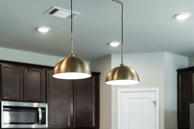 970 Lone Peak Way, Dripping Springs, TX 78620 - kitchen view of stainless steel microwave, dark brown cabinets, and decorative light fixtures