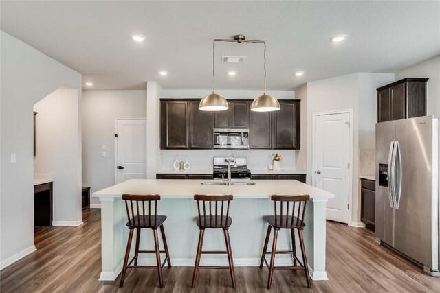 970 Lone Peak Way, Dripping Springs, TX 78620 - kitchen featuring appliances with stainless steel finishes, dark wood-type flooring, backsplash, a center island with sink, and recessed lighting