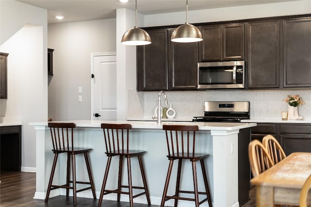 970 Lone Peak Way, Dripping Springs, TX 78620 - kitchen featuring stainless steel appliances, decorative backsplash, dark brown cabinetry, a breakfast bar area, and a center island with sink