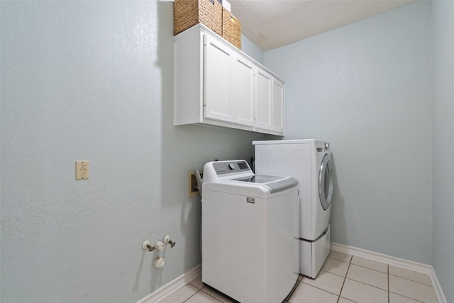 laundry room featuring separate washer and dryer, baseboards, cabinet space, and light tile patterned flooring