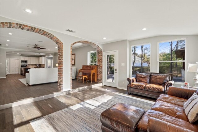 living room with arched walkways, visible vents, recessed lighting, wood finished floors, and ceiling fan