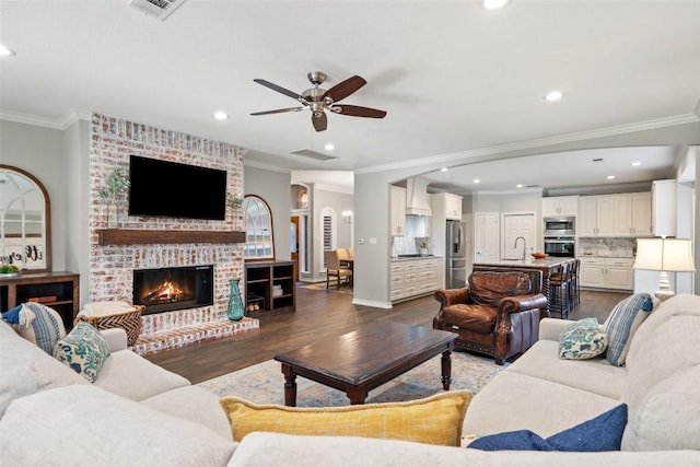 living area featuring ornamental molding, visible vents, ceiling fan, and dark wood finished floors