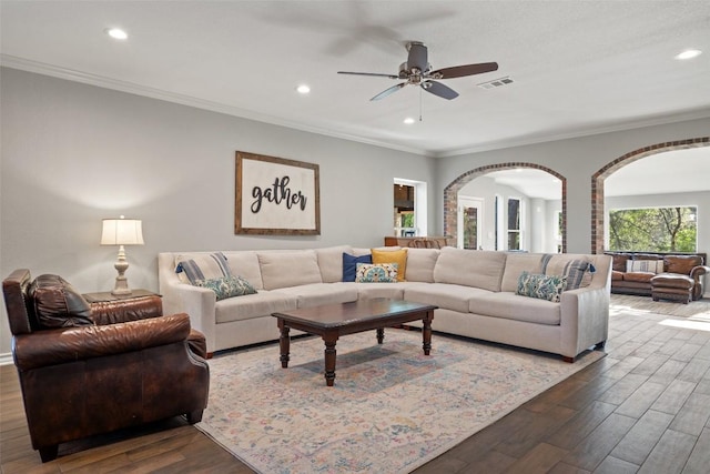 living area featuring a ceiling fan, visible vents, arched walkways, and dark wood-type flooring