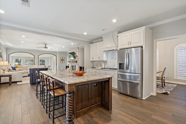 kitchen with ceiling fan, appliances with stainless steel finishes, premium range hood, dark wood finished floors, and ornamental molding