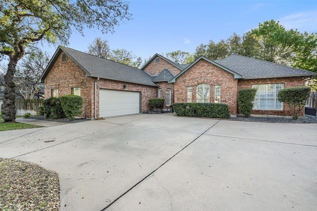 single story home with driveway, an attached garage, fence, brick siding, and roof with shingles