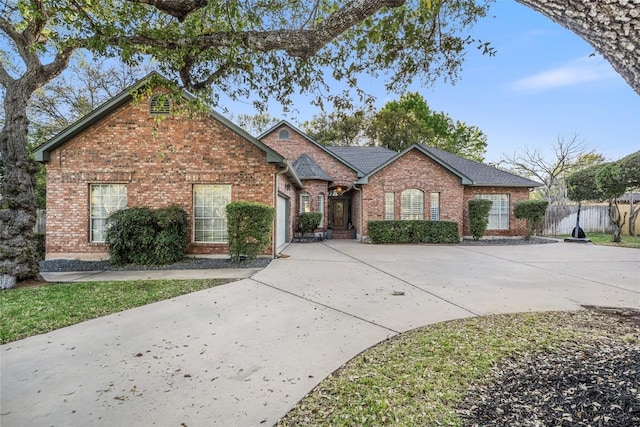 view of front facade with fence, driveway, brick siding, and a garage