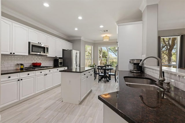 1406 Hunter Ace Way, Cedar Park, TX 78613 - kitchen with stainless steel appliances, a sink, a center island, backsplash, and crown molding