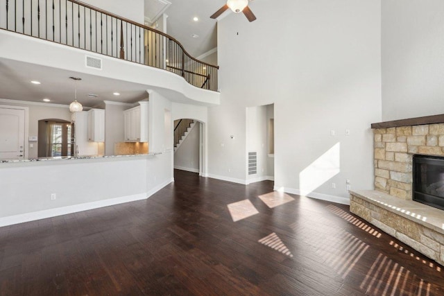 3501 Venezia Vw, Leander, TX 78641 - unfurnished living room with ceiling fan, stairs, a stone fireplace, wood finished floors, and a high ceiling
