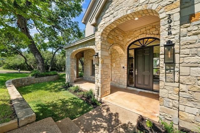 2928 Chatelaine Dr, Austin, TX 78746 - view of exterior entry featuring stone siding, a yard, and covered porch