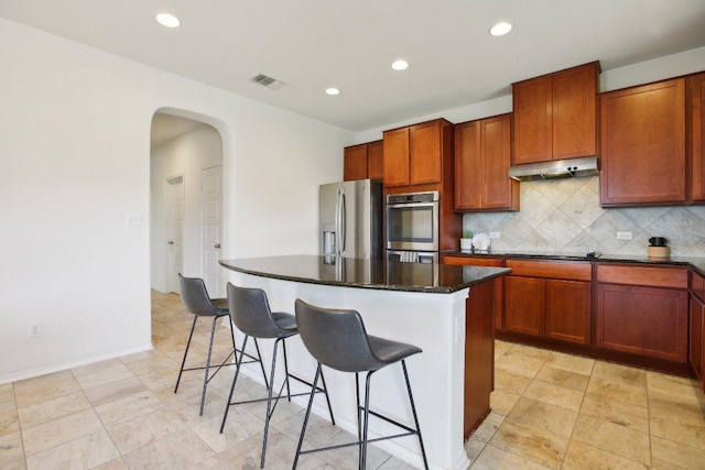 1318 Autumn Sage Way, Pflugerville, TX 78660 - kitchen with stainless steel appliances, under cabinet range hood, arched walkways, a kitchen breakfast bar, and a center island