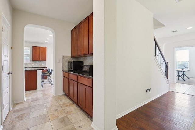 1318 Autumn Sage Way, Pflugerville, TX 78660 - kitchen featuring black microwave, tasteful backsplash, dark countertops, recessed lighting, and arched walkways