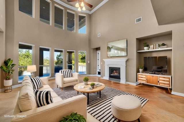 2116 University Club Dr, Austin, TX 78732 - living room featuring built in shelves, a glass covered fireplace, a towering ceiling, plenty of natural light, and baseboards