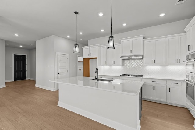 7804 Alouette Dr, Austin, TX 78738 - kitchen with cooktop, light wood finished floors, backsplash, a kitchen island with sink, and recessed lighting