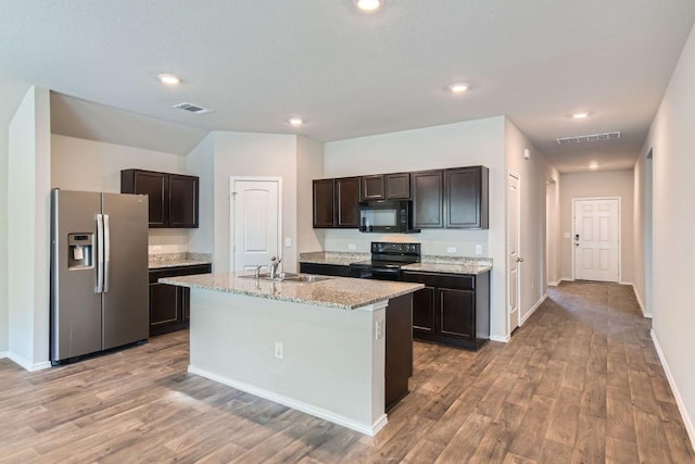 6417 Wideleaf Dr, Austin, TX 78724 - kitchen with black appliances, light wood-style floors, dark brown cabinetry, a center island with sink, and recessed lighting