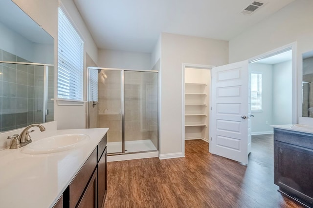8017 Turnberry Ln, Austin, TX 78744 - full bathroom featuring wood finished floors, a shower stall, two vanities, and plenty of natural light