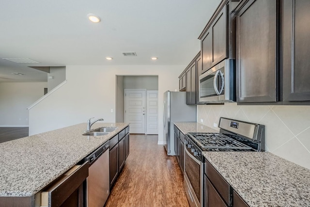 8017 Turnberry Ln, Austin, TX 78744 - kitchen featuring stainless steel appliances, a sink, dark wood finished floors, light stone counters, and recessed lighting