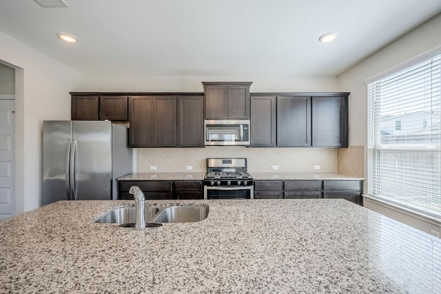 8017 Turnberry Ln, Austin, TX 78744 - kitchen with appliances with stainless steel finishes, a sink, dark brown cabinets, decorative backsplash, and recessed lighting