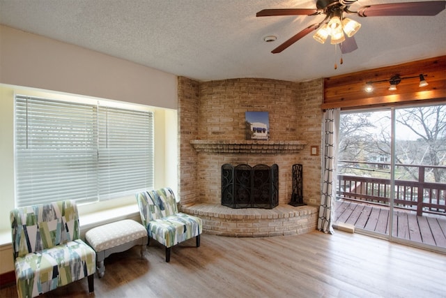 1683 Kuehler Ave, New Braunfels, TX 78130 - living room featuring wood finished floors, a ceiling fan, a brick fireplace, and a textured ceiling