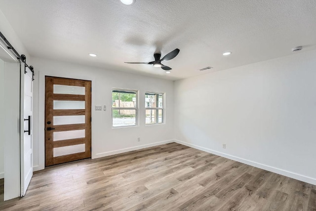 1601 N Redondo Dr, Austin, TX 78721 - unfurnished room featuring a barn door, a ceiling fan, light wood-type flooring, recessed lighting, and a textured ceiling