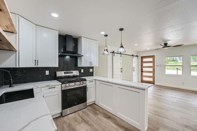 1601 N Redondo Dr, Austin, TX 78721 - kitchen with stainless steel gas range oven, wall chimney range hood, a barn door, a sink, and a peninsula