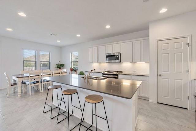 2308 Ringstaff Rd, Leander, TX 78641 - kitchen with appliances with stainless steel finishes, a breakfast bar, a center island with sink, backsplash, and white cabinets