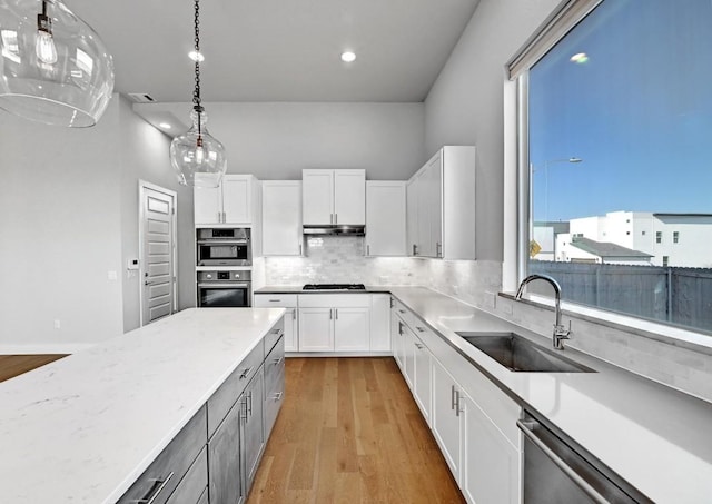 7200 Cordoba Dr, Austin, TX 78724 - kitchen with stainless steel appliances, light wood-style flooring, backsplash, hanging light fixtures, and white cabinets