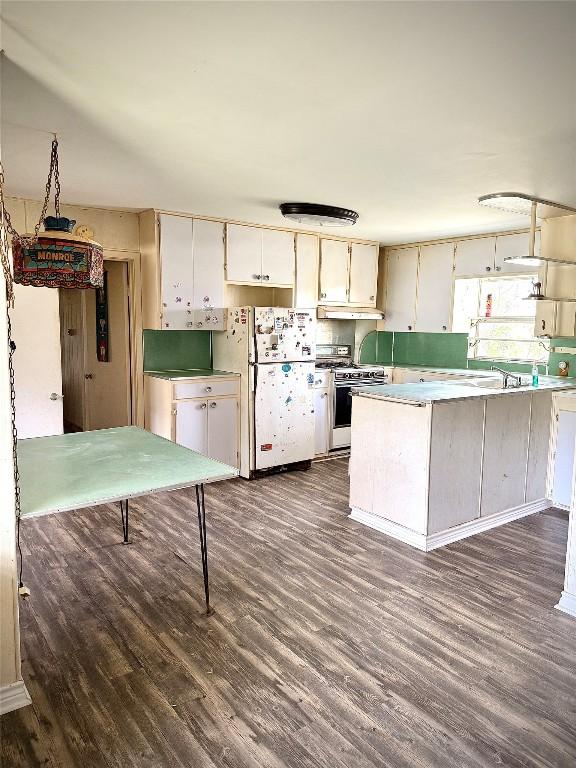 kitchen with gas range, dark wood finished floors, under cabinet range hood, and freestanding refrigerator
