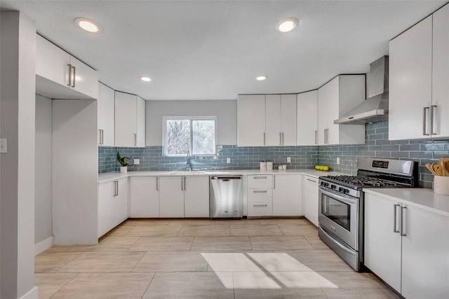 3510 Oak Springs Dr, Austin, TX 78721 - kitchen featuring stainless steel appliances, wall chimney range hood, light countertops, decorative backsplash, and white cabinetry