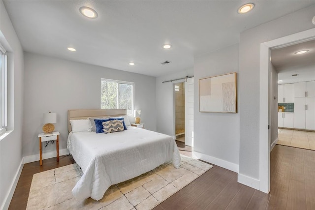 3510 Oak Springs Dr, Austin, TX 78721 - bedroom with a barn door, wood finished floors, recessed lighting, and ensuite bathroom