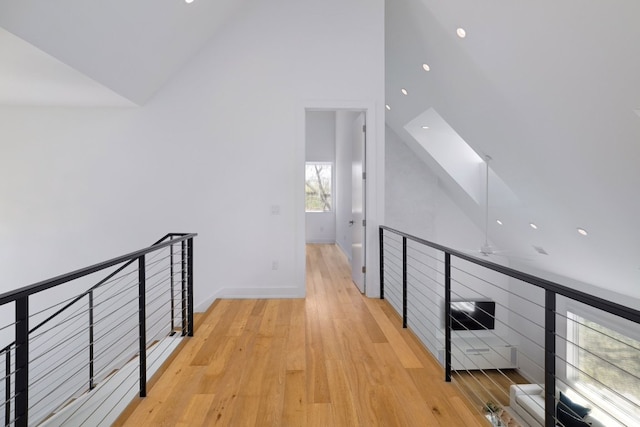 hall with recessed lighting, wood finished floors, vaulted ceiling, an upstairs landing, and baseboards