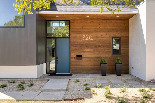 entrance to property featuring roof with shingles