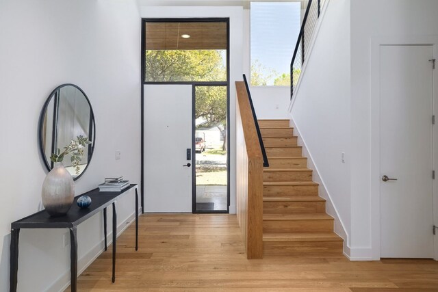 doorway with stairway and light wood-style flooring