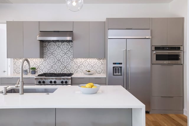 kitchen with gray cabinetry, light countertops, appliances with stainless steel finishes, and extractor fan