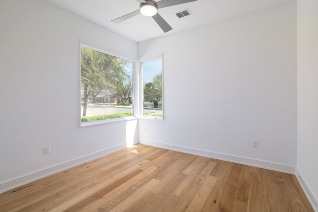 empty room featuring light wood finished floors, visible vents, ceiling fan, and baseboards