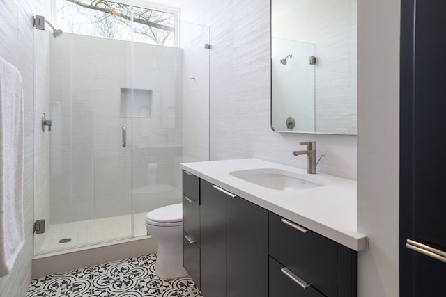 bathroom featuring tile patterned flooring, a shower stall, tile walls, toilet, and vanity