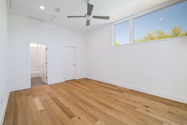 unfurnished bedroom with connected bathroom, light wood-style floors, attic access, baseboards, and visible vents