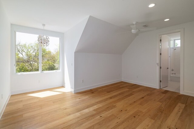 additional living space featuring recessed lighting, light wood-style flooring, vaulted ceiling, ceiling fan with notable chandelier, and baseboards