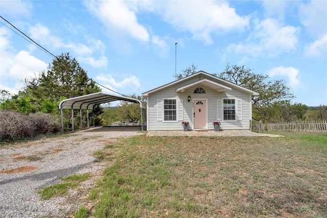 5898 River Oaks Dr, Kingsland, TX 78639 - bungalow-style house featuring gravel driveway, a detached carport, a front yard, and fence
