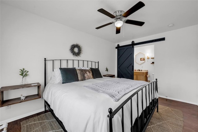 5898 River Oaks Dr, Kingsland, TX 78639 - bedroom featuring baseboards, a barn door, a ceiling fan, ensuite bathroom, and wood finished floors