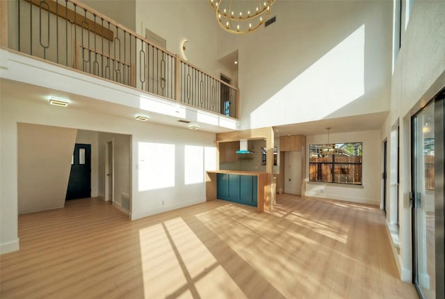 1701 Indian Camp Trl, Round Rock, TX 78681 - unfurnished living room with a chandelier, a towering ceiling, light wood-type flooring, and healthy amount of natural light