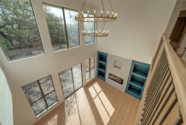 1701 Indian Camp Trl, Round Rock, TX 78681 - staircase with a chandelier, built in shelves, a towering ceiling, and wood finished floors