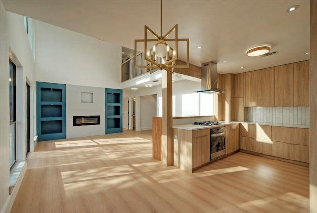 1701 Indian Camp Trl, Round Rock, TX 78681 - kitchen with wall chimney range hood, modern cabinets, light countertops, light wood-style flooring, and open floor plan