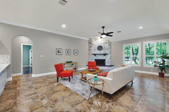104 Standing Oak Dr, Georgetown, TX 78633 - living room with a ceiling fan, a stone fireplace, baseboards, ornamental molding, and arched walkways