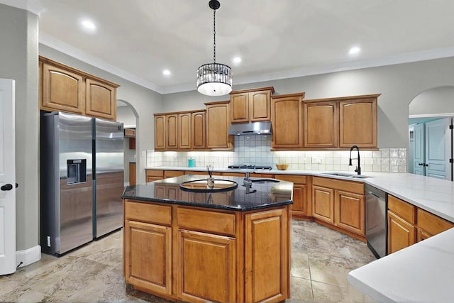104 Standing Oak Dr, Georgetown, TX 78633 - kitchen with arched walkways, stainless steel appliances, crown molding, brown cabinets, and decorative backsplash