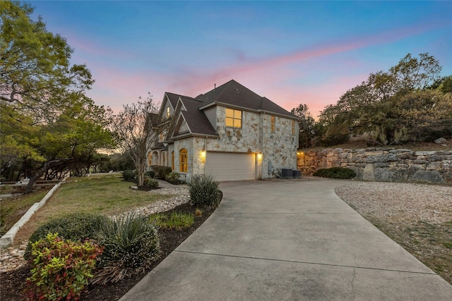 1420 Mirador, Leander, TX 78641 - property exterior at dusk with stone siding, an attached garage, concrete driveway, and a yard